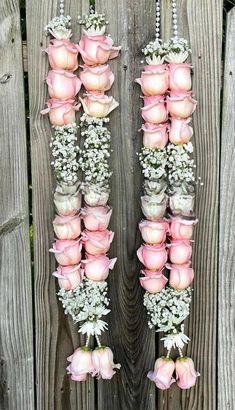 pink roses and baby's breath hanging from a wooden fence