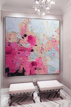 two white benches sitting in front of a large painting on the wall with pink and blue colors