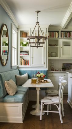 a kitchen with a white table and blue bench next to a book shelf filled with books