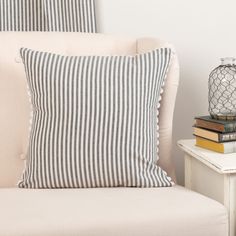 a striped pillow sitting on top of a white chair next to a table with books