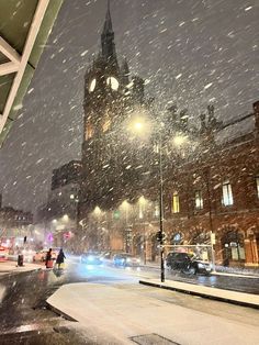 a snowy night in the city with people walking and cars driving down the street,