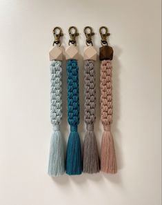 four key chains with tassels hanging from them on a white wall and two are attached to each other