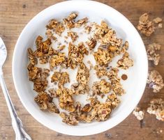 a white bowl filled with granola and yogurt on top of a wooden table