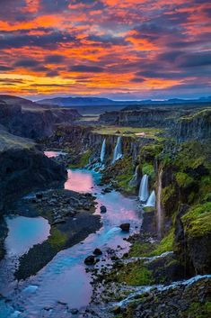 the sun is setting over a waterfall in iceland, with water running down it's side