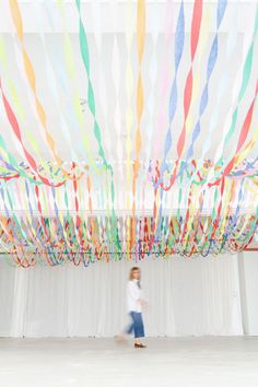 a girl is walking in front of a curtain with streamers hanging from the ceiling