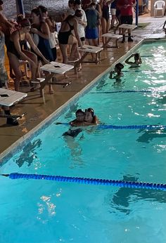 people are watching swimmers in the swimming pool