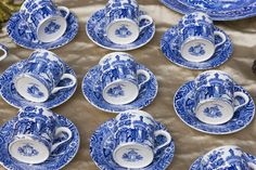 many blue and white cups and saucers on a table