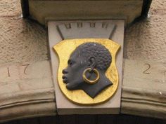 a close up of a clock on the side of a building with a statue of a woman's head