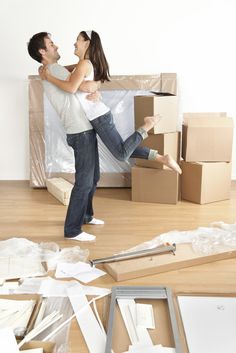 a man and woman standing in front of boxes on the floor with their arms around each other