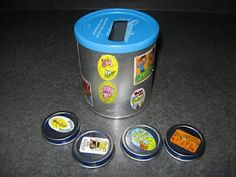 four small tins with various stickers on them sitting next to each other in front of a black counter top