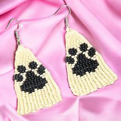 two pairs of beaded earrings with black and white beads on pink satin background,