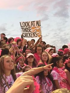 a group of girls in pink outfits holding up signs and pointing to the side with their hands