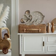 there is a basket with lights on top of the table next to a mirror and stuffed animals