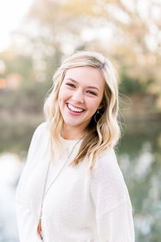 a woman smiling and standing in front of water