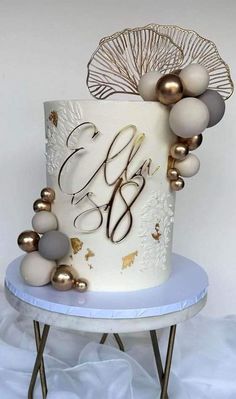 a white and gold wedding cake with the initials on it's side sitting on a table