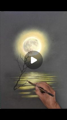 a person is drawing a tree on the water with a light shining in the background