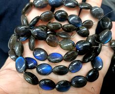 a person holding some kind of blue and black stone beads in their hand, with other rocks around them