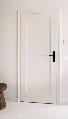 an empty room with a wooden stool and white door