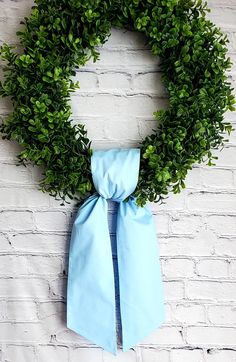 a green wreath with a blue tie hanging on a brick wall