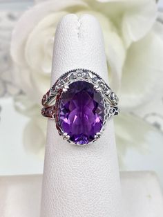 Natural Purple Amethyst Ring Set Edward Design#70 Made To Order This filigree ring is an Edwardian antique reproduction in sterling silver set with a 4 carat natural Rainbow purple amethyst gemstone solitaire. This faceted cut oval gem is 14mm x 10mm. This ring sits 7mm off the finger. The inside of the band is marked 925 for sterling silver. This ring now has a matching floral accompanying curved band. This band was specially designed to fit this ring perfect. You can elect to purchase just the Amethyst Rings With Diamond Accents, Oval Shape, Adjustable Oval Rings With Gemstone Accents, Stackable Rings With Stone Setting For Anniversary, Anniversary Stone Setting Stackable Rings, Oval Amethyst Ring With Vs Clarity For Wedding, Ring Purple, Purple Amethyst Ring, Vintage Style Rings, Amethyst Gem