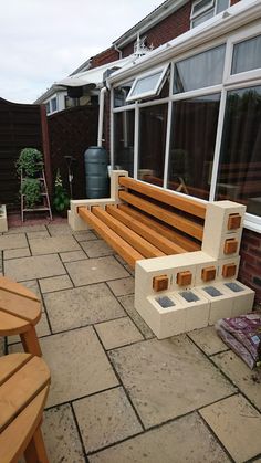 a wooden bench sitting on top of a brick patio next to a tall glass window