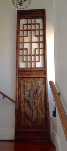 an old wooden door in the corner of a room with a light fixture hanging above it