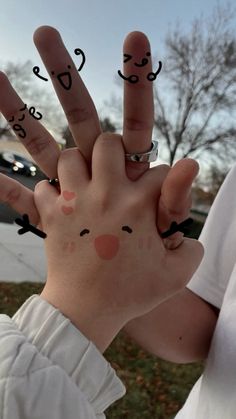 a person holding up their fingers with faces drawn on them