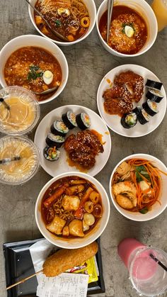 several bowls of food are arranged on a table with chopsticks and drinks in front of them