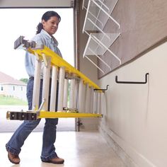 a woman walking up the side of a building with a ladder attached to her back