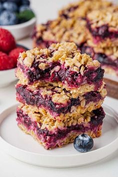 berry crumb bars stacked on top of each other next to berries and strawberries