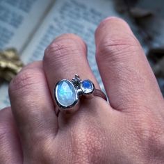 everyday jewelry, moonstone ring, silver jewelry, handmade ring, ring lover, crystal ring, minimalist jewelry, metalsmithing ring This moonstone ring is a simple, everyday piece! There's a triple silver embellishment that resembles a twinkling star in between the stones. It sits on a rounded band.  All components of the ring are hand fabricated in sterling silver and plated with 18k white gold. The ring is a size 7 US.  The back settings of the stones are open to allow natural light to pass through. Please message me if you have any questions. Handmade Minimalist Moonstone Promise Ring, Handmade Minimalist Moonstone Open Ring, Handmade Minimalist Moonstone Ring, Handmade Minimalist Open Moonstone Ring, Handmade Modern Moonstone Ring In Sterling Silver, Modern Handmade Sterling Silver Moonstone Ring, Silver Minimalist Moonstone Crystal Ring, Minimalist Silver Moonstone Ring In Sterling Silver, Minimalist Moonstone Opal Ring In Silver