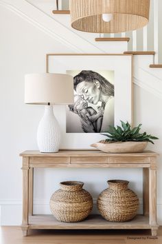 a table with two vases and a painting on the wall above it next to a lamp