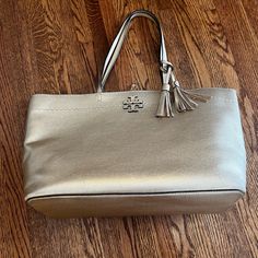 Tory Burch Mcgraw Tote Metallic Gold Good Used Condition. Some Wear On Corners Of Bag And Minor Wear On Handles. Minor Smudging On Exterior And Pocket. Clean Interior With Some Light Marking - Have Not Tried To Remove. Overall In Good Condition And Has Only Been Used A Handful Of Times For A Trip. From A Limited Edition Holiday Release. Metallic Gold Color, Tory Burch Bags, Tory Burch Bag, Metallic Gold, Tory Burch, Gold Metal, Limited Edition, Handles, Bag Lady