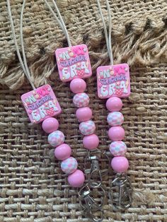 three pink and white beads with tags attached to them