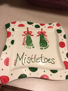 a ceramic plate with two feet on it and the words mistletoes written in green