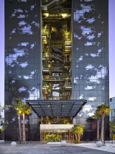 the entrance to an office building with stairs going up it's side and palm trees in front