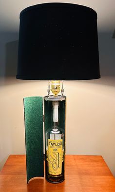 a lamp that is on top of a wooden table with a bottle in it next to a book