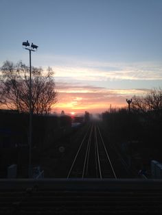 the sun is setting over some train tracks