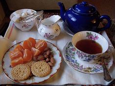 a tray with tea, crackers, nuts and other food on it next to a blue teapot