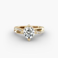 a yellow gold engagement ring set with a round brilliant cut diamond and pave diamonds