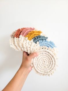 a hand is holding several pieces of yarn in different colors and sizes on a white background