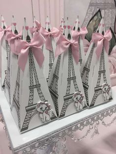 four small bags with pink bows are on a table in front of the eiffel tower