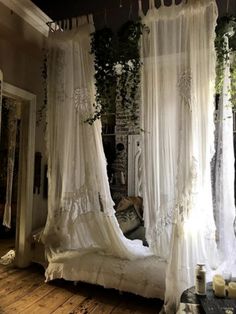 a canopy bed with sheer curtains hanging from it's sides