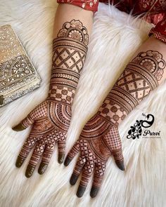 two hands with henna tattoos on them, one is showing off the intricate design