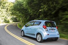 a small blue car driving down the road