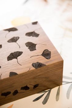 a wooden box sitting on top of a table next to flowers and leaves painted on it