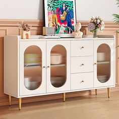 a white cabinet with two glass doors and some flowers on the sideboard next to it