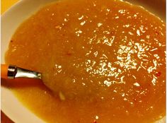 a bowl of soup with a spoon in it on a yellow tableclothed place mat