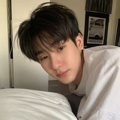 a young man laying on top of a bed next to a white pillow covered in sheets