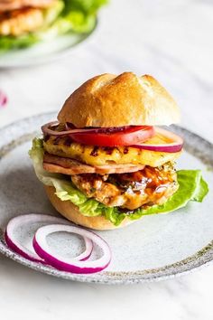 a chicken sandwich with lettuce, tomato and onion on a white platter